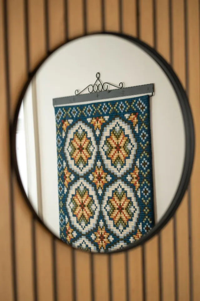 A round mirror and a woven wall hanging