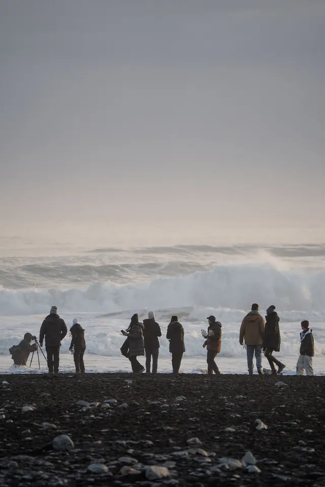 Travellers on the black sand at Diamond Beach