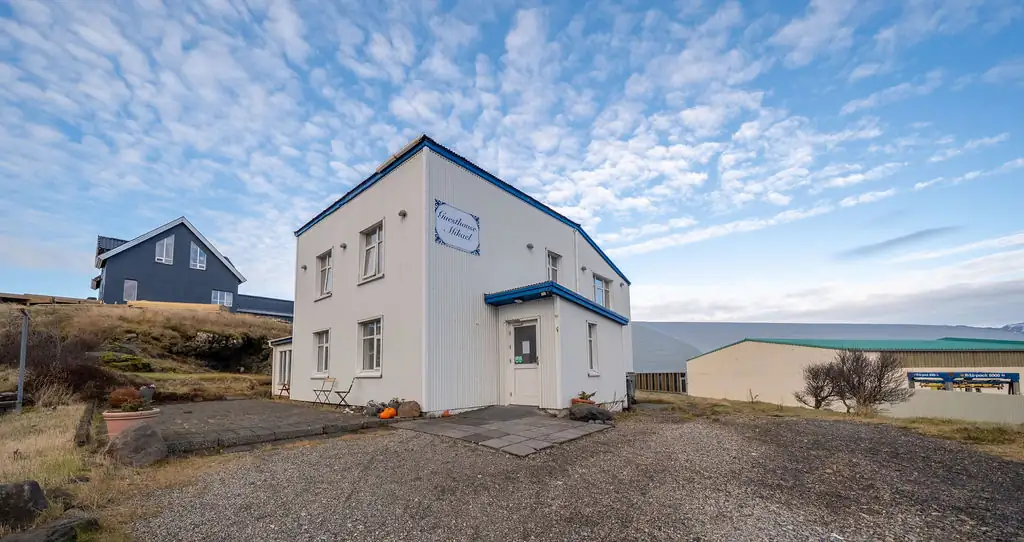 The white and blue Guesthouse Mikael building under an open Icelandic sky