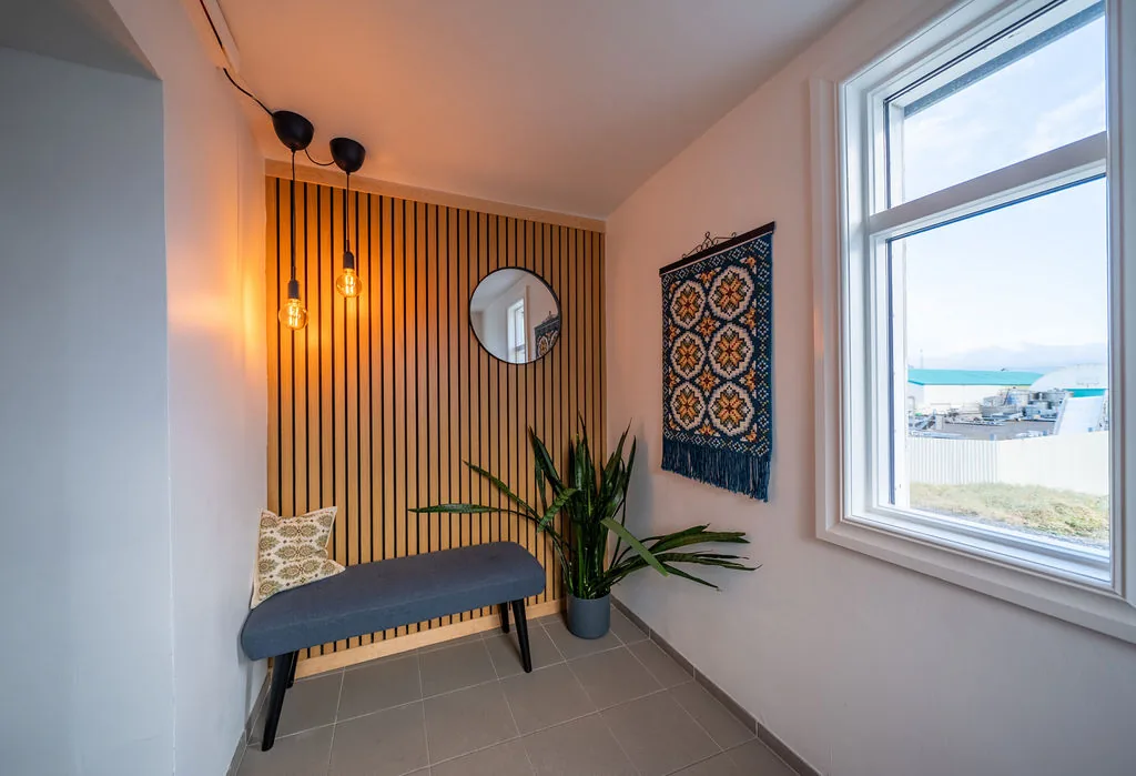 The entrance with a bench, a slatted timber wall and a window onto the fjord